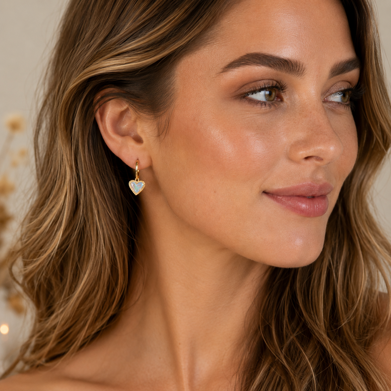 Kendra Scott Ari Heart Gold Dichroic Glass Huggie Earrings worn on model with iridescent heart charm detail