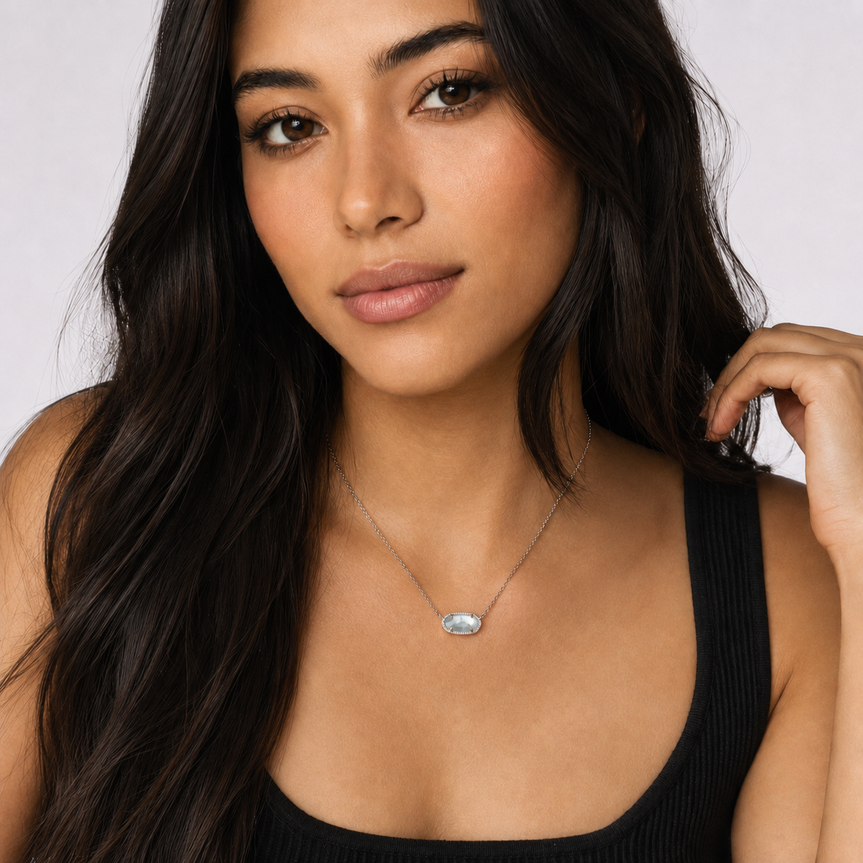 Woman wearing Kendra Scott Elisa Short Pendant Necklace in Rhodium Light Blue Illusion with a light blue oval pendant on a delicate rhodium chain