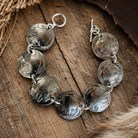 Genuine Domed Indian Heads & Tails Nickel Bracelet with sterling silver hardware displayed on a rustic wood surface.