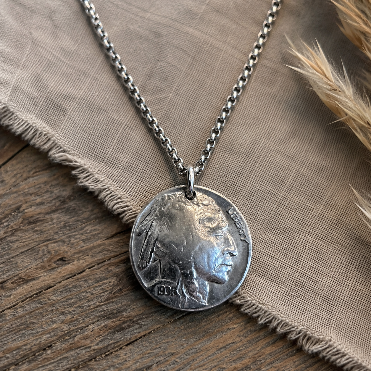 Genuine Indian Head nickel pendant necklace on an 18-inch chain, displayed on rustic fabric and wood.