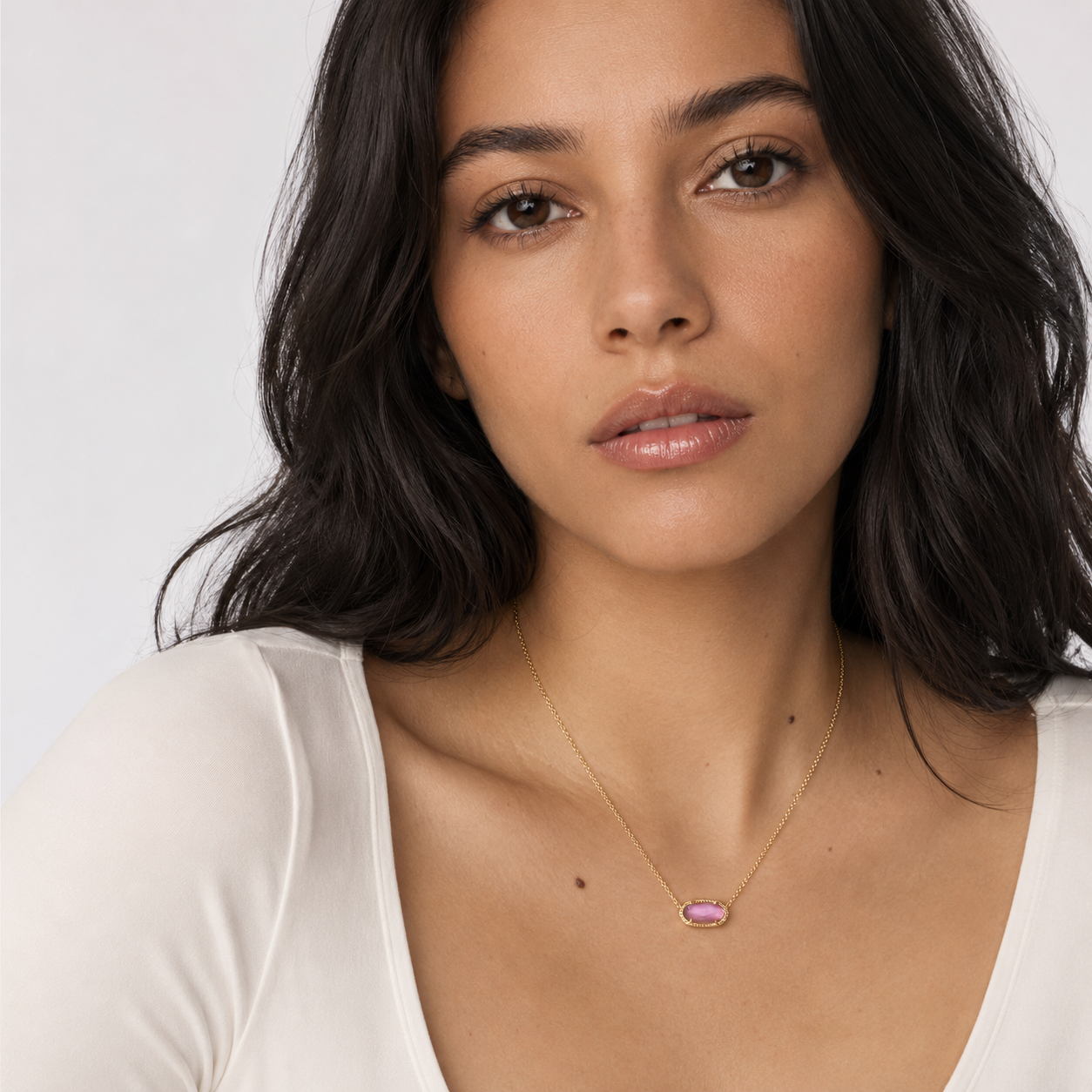 Woman wearing Kendra Scott Elisa Short Pendant Necklace in Gold Azalea Illusion with a pink oval pendant on a delicate gold chain